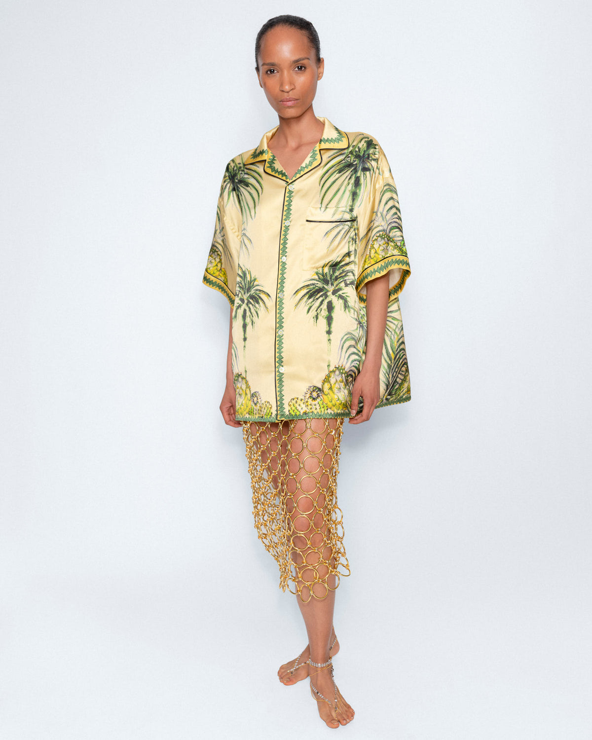 Yellow Palm Print Shirt worn with a gold chain skirt, full length