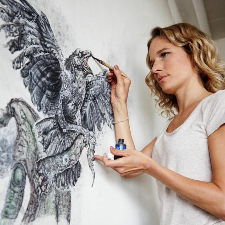 Ginny Litscher painting a raven on a wall