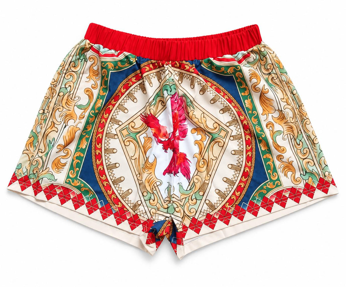 The Phoenix Silk Shorts, front: red waistband and a baroque print in cream, gold, green and blue with a red phoenix